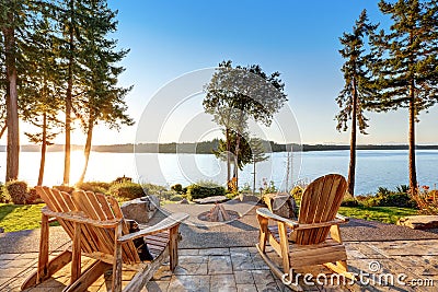 Back yard of waterfront house with adirondack chairs and fire pit Stock Photo