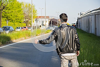 Back of young man, hitchhiker waiting on roadside Stock Photo