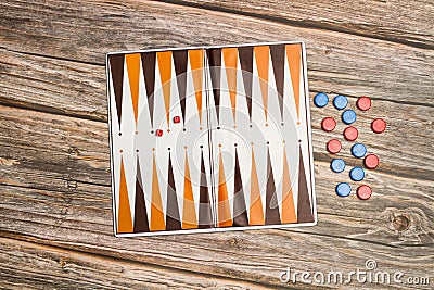 A backgammon board with red and blue checkers and small dices on a wooden table Stock Photo