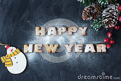 Background with branch of christmas tree, snowmen and baked gingerbread words happy new year with powdered sugar Stock Photo