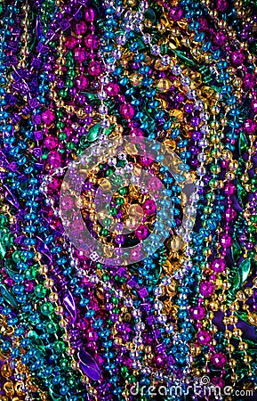 A background of brightly colored Mardi-Gras beads on a purple b Stock Photo