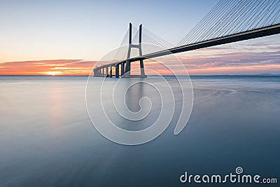 Background with colourful sunrise on the Lisbon bridge. The Vasco da Gama Bridge is a landmark, and one of the longest bridges in Stock Photo