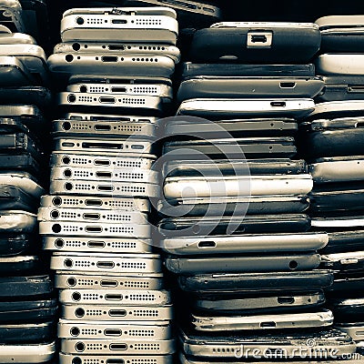 Background of damaged mobile phones. A bunch of broken smartphones. Used phones stacked on top of each other. Repair services and Stock Photo