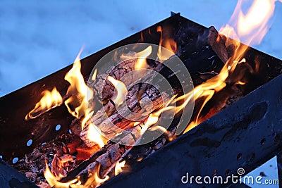 Background of fire and black wood. Dark grey, black white coals on bright fire inside metal brazier. Wood burning in the brazier. Stock Photo