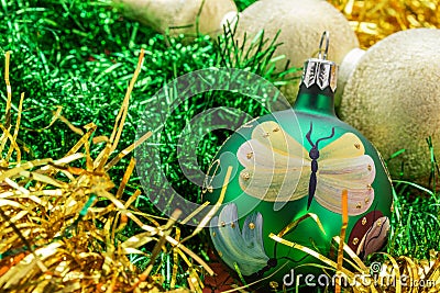 Background in the form of Christmas tree decorations - a large green painted ball, light beads, golden and green rain Stock Photo