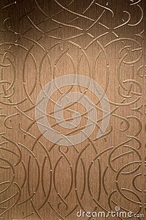 Background of gold foil with scrollwork design under soft lighting Stock Photo