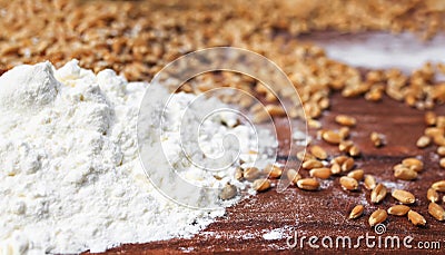 Background of Golden wheat grains and white crumbling flour scattered on wooden table Stock Photo