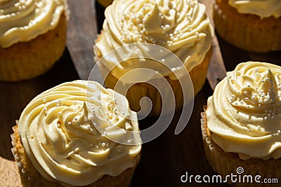 A background image of five delicious cream colored cupcakes on a wooden board Stock Photo