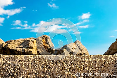 On a stone wall, in focus and out of focus are small stones against a blue sky that give the impression of a desert. Stock Photo