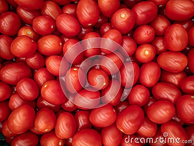 A background of a large number of small red tomatoes. Background from vegetables on a shop window. Stock Photo