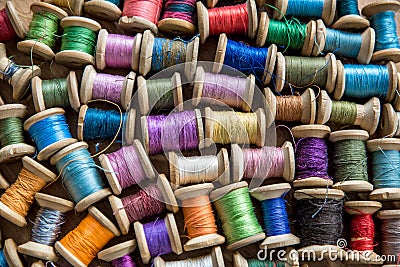 The background is made of colorful threads on wooden vintage reels. Skeins of colored thread. Top view Stock Photo