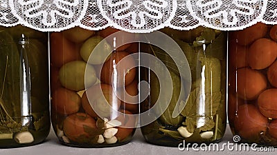 Background from a number of alternating glass jars with fermented cucumbers and tomatoes in the style of rustic Stock Photo