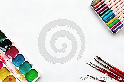 Background of palette of watercolor paints, brushes, colorful pencils on a white paper Stock Photo