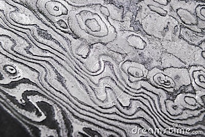 Background with pattern of damask steel. Close up. Macro shot of a damascus knife blade texture. Damascus steel pattern. Metal and Stock Photo