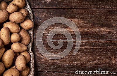 Background with raw potatoes on jute bag and wooden table top Stock Photo