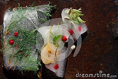 Background of red berry of hawthorn and twig of juniper frozen in ice Stock Photo