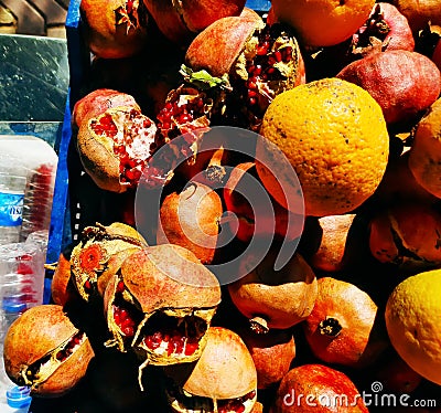 Background of ripe torn pomegranates and an orange in the oriental market. Fruit prepared for making freshly squeezed juice Stock Photo