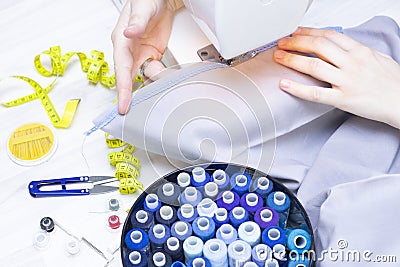 Background sewing. Hands of a seamstress on a sewing machine. Stock Photo