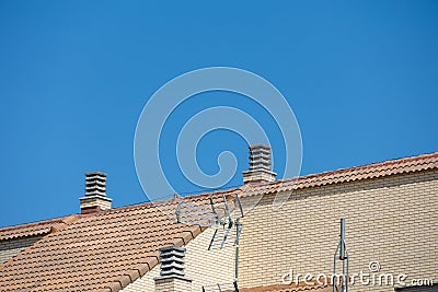 Background with spanish tiled roofs of houses against a cloudless blue sky Stock Photo