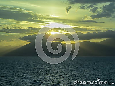 Background. Sunset. Sea and mountains. The sun`s rays make their way through the clouds Stock Photo