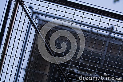 Background or texture in the blue sky of a crossbeam from building lattices. View of balconies from below. Cage, grid, wire. Stock Photo