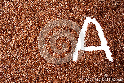 Background with texture of brown flax seeds with a white letter of vitamin A Stock Photo