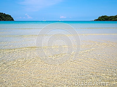 Background of transparent crystal blue sea water surface ripple over sand with sun reflection in summer. Water background. Ocean Stock Photo