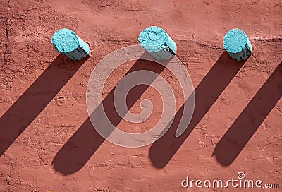 Background - Turquoise corbels and their long shadows on an orange stucco wall on southwestern style building Stock Photo