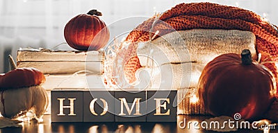 Background with warm sweaters and the inscription HOME. Pile of knitted clothes with leaves, pumpkins. Coziness. Autumn concept Stock Photo