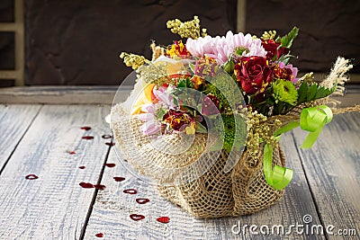 Background wedding or Valentine`s Day. Basket bouquet of roses and chrysanthemums on a vintage wooden background. Stock Photo