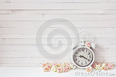 Background with white alarm clock and small pink roses on white Stock Photo