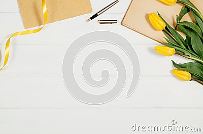 Background with yellow tulips, blank notepad on white wooden table Stock Photo