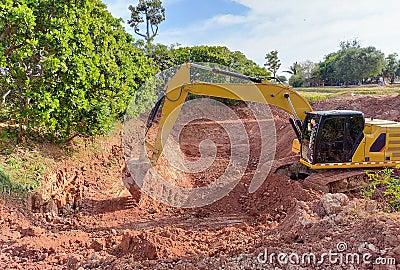 Backhoe bucket digging the soil at agriculture farm to make pond. Crawler excavator digging at shale layer. Excavating machine. Stock Photo