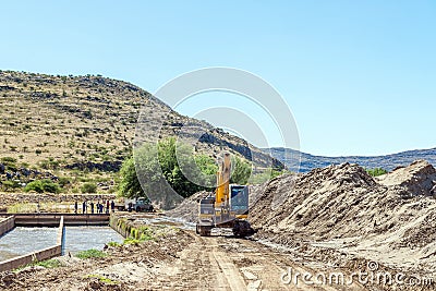 Backhoe loader clearing sand blocking canal at Boegoeberg Dam Editorial Stock Photo