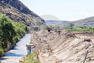 Backhoe loaders clearing sand blocking canal at Boegoeberg Dam Editorial Stock Photo