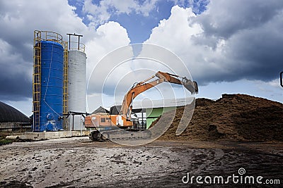 Backhoe working with moutain of waste in a factory Stock Photo