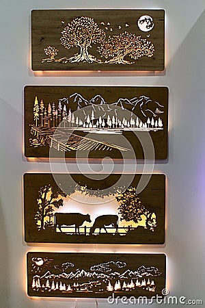 Backlit carved pictures of cows, mountain landscape and night landscape, made by LiGo company, displayed on creamy white wall Editorial Stock Photo