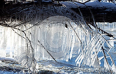 backlit icicles over flowing water Stock Photo
