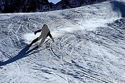 Backlit silhouette of man in action practicing ski going fast and aggressive down snow slope winter sport Stock Photo
