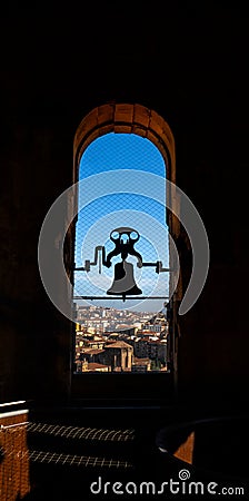 Backlit silhouette of restored bronze bell of the Torre de la Clerecia with evening sunlight streaming through the arched window Stock Photo