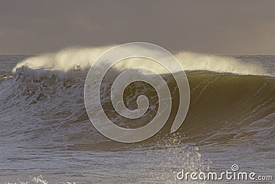 Backlit stormy wave spray at sunset Stock Photo
