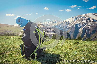 Backpack stands on top of a beautiful mountain, hiking, green valley Stock Photo