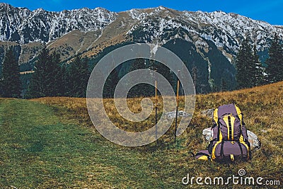 Backpack and walking sticks on mountain trail Stock Photo