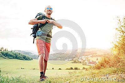 Backpacker traveler fastening sternum strap on backpack and preparing for trekking at summertime sunny day Stock Photo