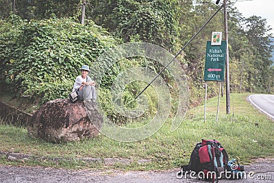 Backpacker waiting for hitchhike on the road for Kubah National Park, West Sarawak, Borneo, Malaysia. Stock Photo