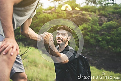Backpackers man getting help to friend climb at nature,Helping hand,Overcoming obstacle concept Stock Photo