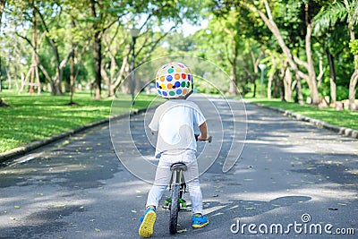 Backside of Asian 2 years toddler boy child wearing safety helmet learning to ride first balance bike Stock Photo