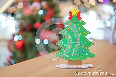 Backside Christmas tree paper craft decoration on the wood table with blur big Christmas tree behide Stock Photo