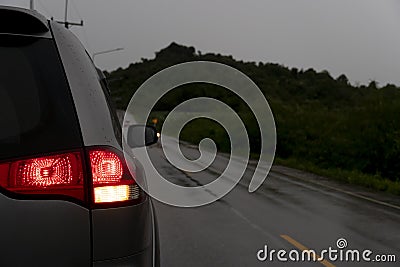 Backside of family gray car stop on asphalt road with rain. Stock Photo