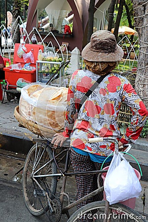 Backside of kite cracker seller, kite cracker in the clear plastic bags on the threshing basket for sale on her bicycle Editorial Stock Photo